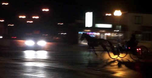 car and horse and buggy meet on rainy night